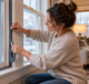 Homeowner applying weatherstripping around a winter window